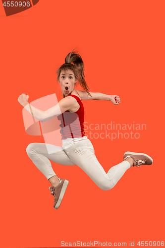 Image of Freedom in moving. Pretty young woman jumping against orange background