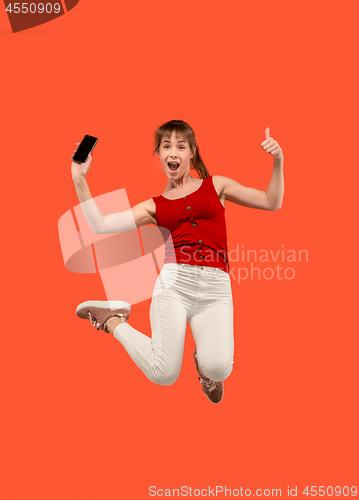 Image of Full length of pretty young woman with mobile phone while jumping