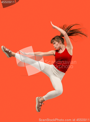 Image of Freedom in moving. Pretty young woman jumping against orange background