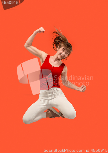 Image of Freedom in moving. Pretty young woman jumping against orange background