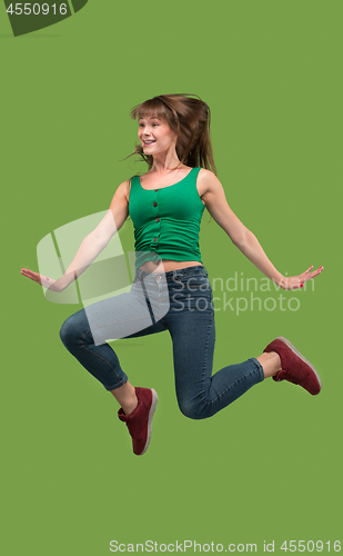 Image of Freedom in moving. Pretty young woman jumping against orange background