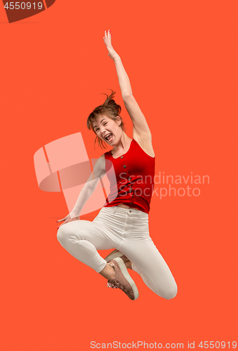 Image of Freedom in moving. Pretty young woman jumping against orange background