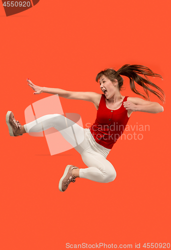 Image of Freedom in moving. Pretty young woman jumping against orange background