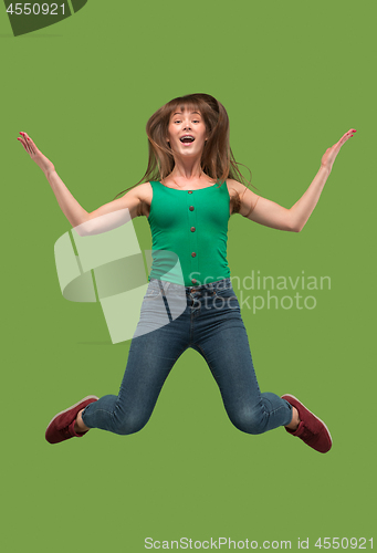 Image of Freedom in moving. Pretty young woman jumping against orange background