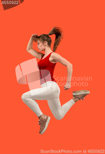 Image of Freedom in moving. Pretty young woman jumping against orange background