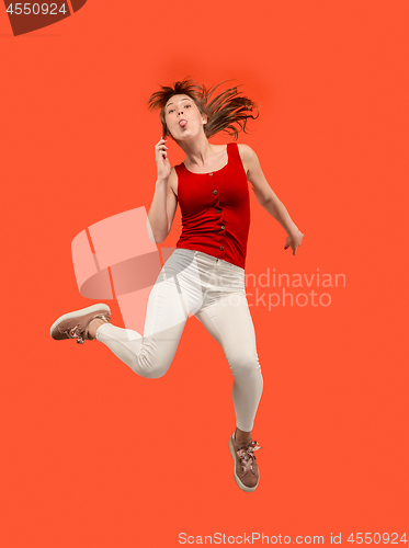 Image of Full length of pretty young woman with mobile phone while jumping