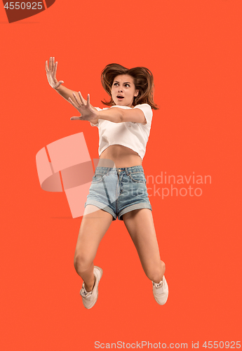 Image of Freedom in moving. Pretty young woman jumping against orange background