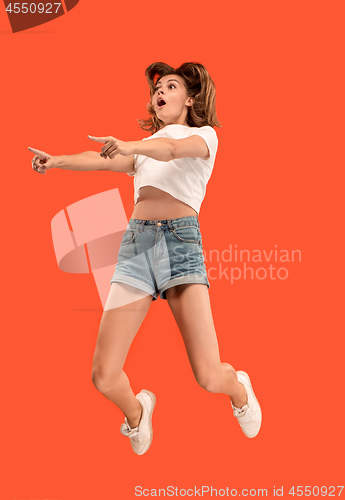 Image of Freedom in moving. Pretty young woman jumping against orange background