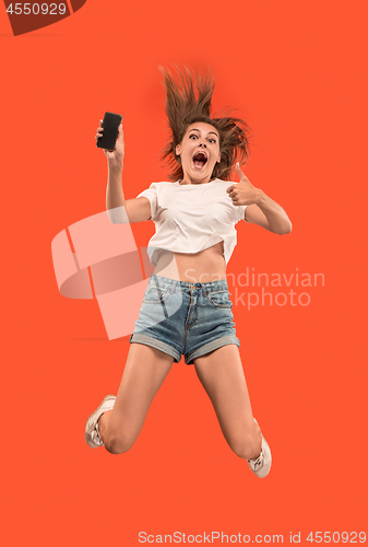 Image of Full length of pretty young woman with mobile phone while jumping