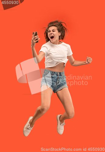 Image of Full length of pretty young woman with mobile phone while jumping