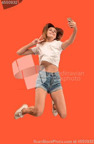 Image of Full length of pretty young woman with mobile phone while jumping