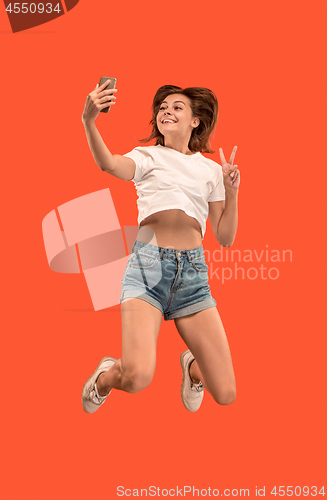 Image of Full length of pretty young woman with mobile phone while jumping