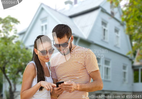 Image of happy couple with smartphone in summer over house