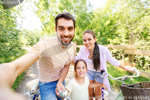 Image of happy family with bicycles taking selfie in summer