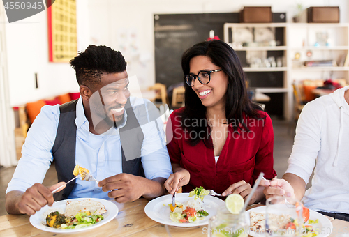 Image of happy friends eating and talking at restaurant