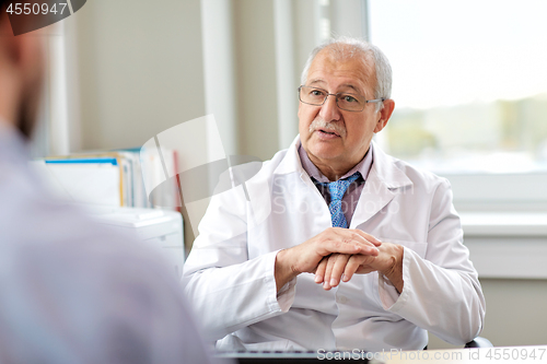 Image of senior doctor talking to male patient at hospital