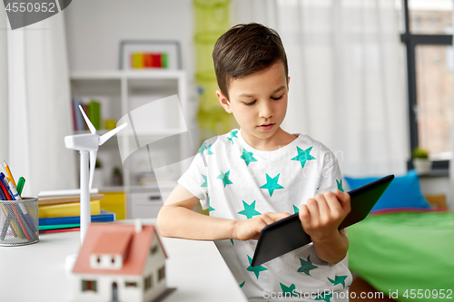 Image of boy with tablet, toy house and wind turbine