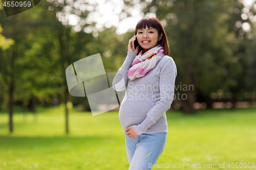 Image of pregnant asian woman calling on smartphone at park