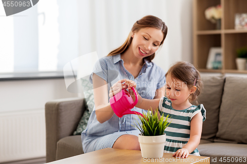 Image of pregnant mother and daughter watering home plant