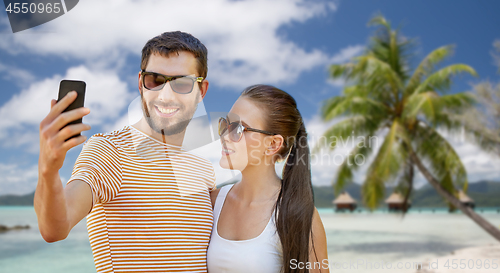 Image of happy couple taking selfie by smartphone on beach