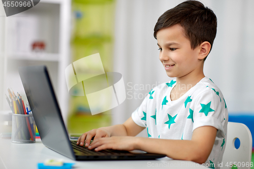 Image of student boy typing on laptop computer at home