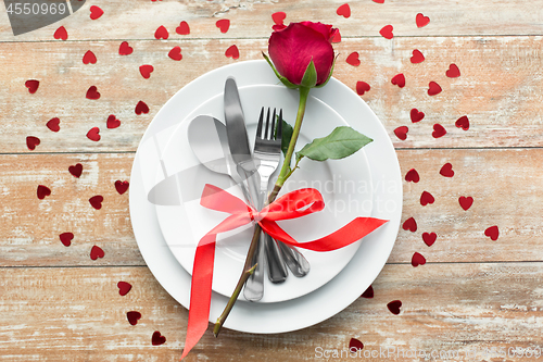 Image of close up of red rose flower on set of dishes