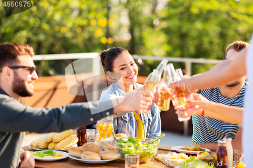 Image of happy friends toasting drinks at rooftop party