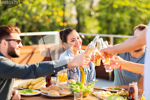 Image of happy friends toasting drinks at rooftop party