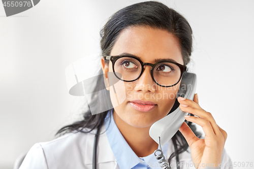 Image of doctor in glasses calling on phone at hospital