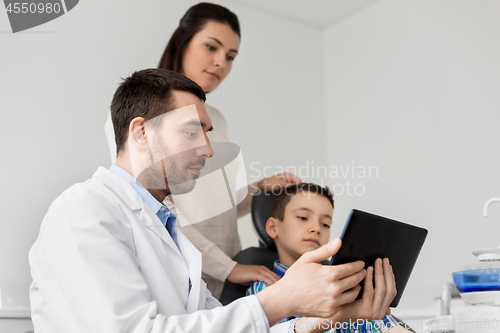 Image of dentist showing tablet pc to kid at dental clinic