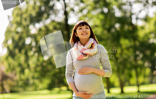 Image of happy pregnant asian woman at park