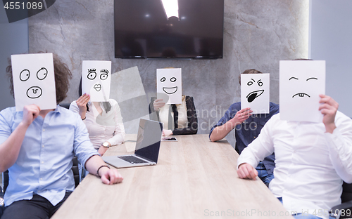 Image of startup business team holding a white paper over face