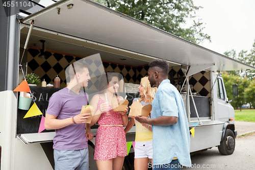 Image of happy friends with drinks eating at food truck