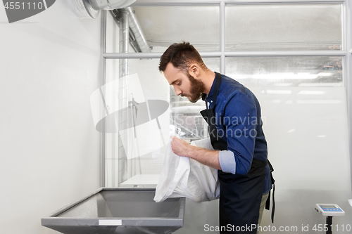 Image of brewer pouring malt into mill at beer brewery