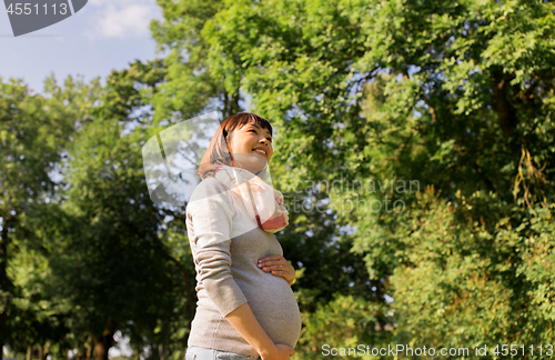 Image of happy pregnant asian woman at park