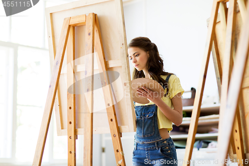 Image of student girl with easel painting at art school