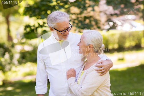 Image of happy senior couple hugging at summer park