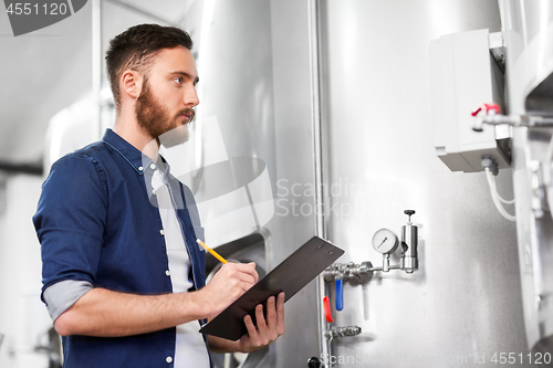 Image of man with clipboard at craft brewery or beer plant