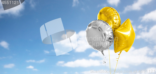 Image of three gold and silver helium balloons on white