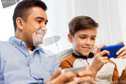 Image of happy father and son with smartphones at home