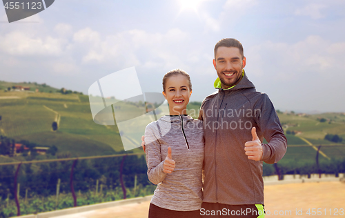 Image of couple showing thumbs up over country landscape