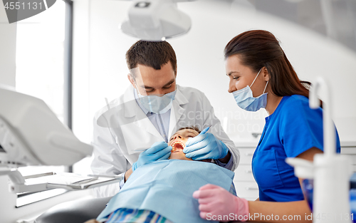 Image of dentist checking for kid teeth at dental clinic