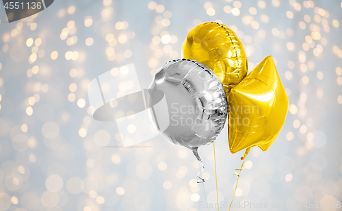 Image of three gold and silver helium balloons on white