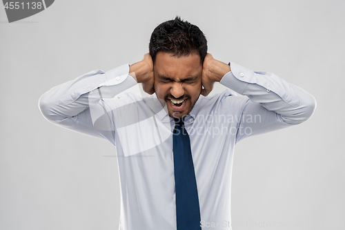 Image of screaming businessman covering ears with hands