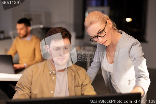 Image of business team with computer working late at office