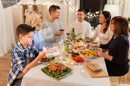Image of boy with smartphone at family dinner party