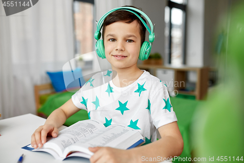 Image of boy in headphones with textbook learning at home