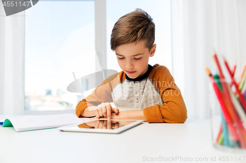 Image of student boy with tablet pc and notebook at home