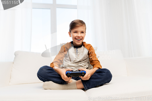 Image of happy boy with gamepad playing video game at home