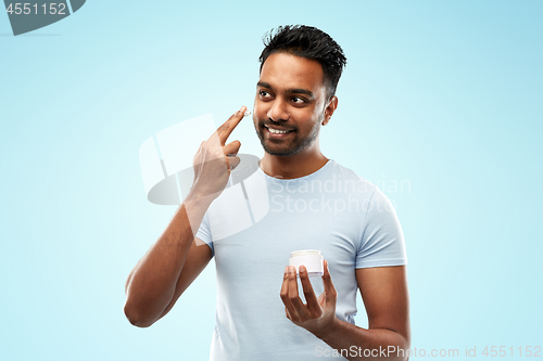 Image of happy indian man applying cream to face